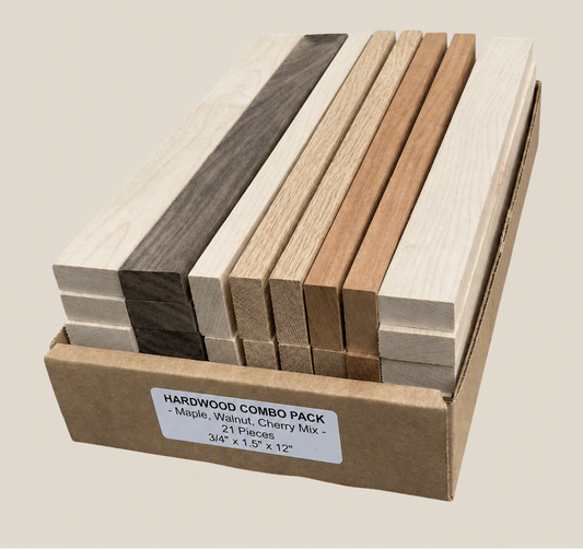 A cardboard box containing 21 straight hardwood pieces in mixed species, including maple, walnut, and cherry. The wood pieces show different natural grain patterns and tones, ranging from light cream to dark brown.
